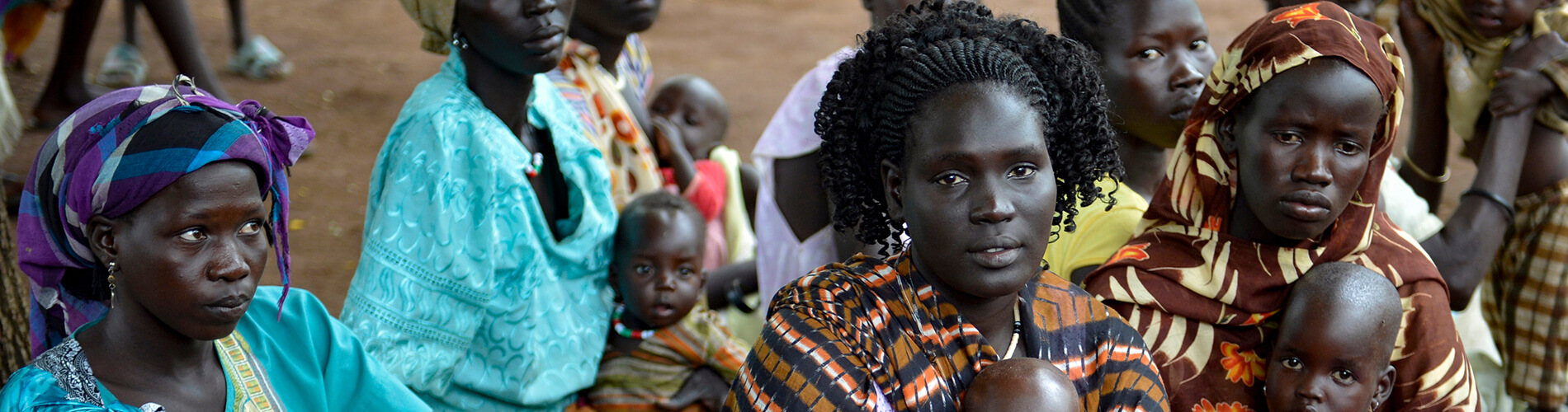 Sudanese women sitting on ground with their kids