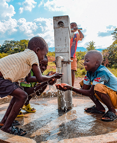 Black kids enjoying water from the pump