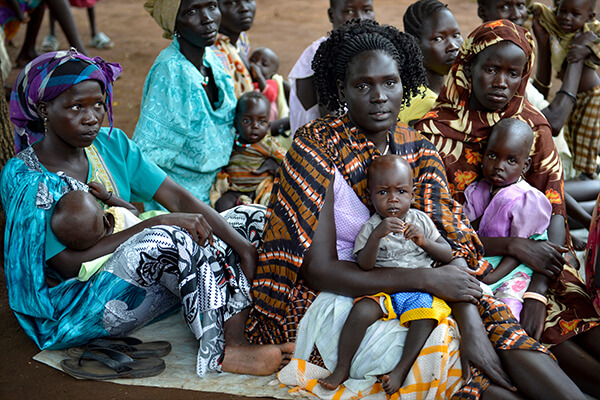 Sudanese women sitting on ground with their kids